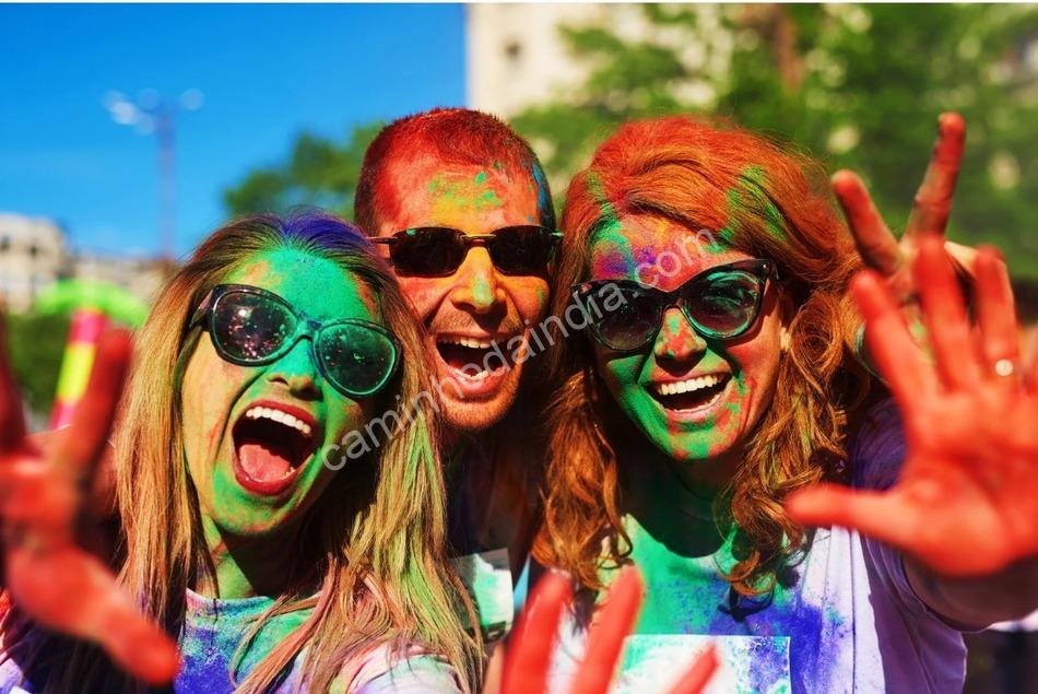 Grupo de estrangeiros participando da festa de Holi na Índia, jogando pó colorido