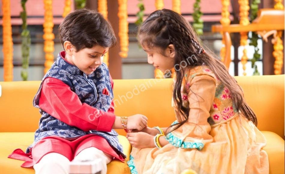Irmão mais novo olhando atentamente enquanto a irmã amarra o rakhi em sua mão durante o Raksha Bandhan