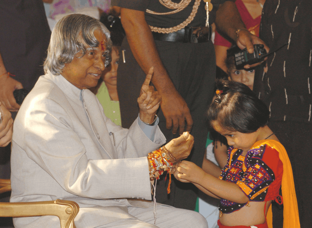 Uma menina amarra um rakhi no pulso do presidente da Índia, Dr. A. P. J. Abdul Kalam, durante a celebração do Raksha Bandhan em Nova Délhi, em 2005.