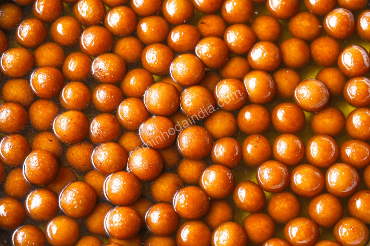 Gulab jamun deixado na calda para absorção completa do açúcar aromatizado